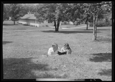 Georgetown College; campus scene; exterior; man and woman laying                             on grass (lawn) reading a book