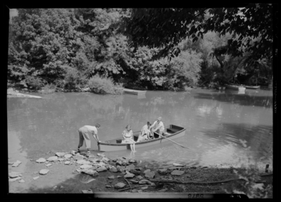 Georgetown College; exterior; river (creek); group seated in a                             row boat; man launching row boat; empty row boats along the water's                             edge