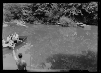 Georgetown College; exterior; river (creek); group seated in a                             row boat; person on shore waving to boat occupants