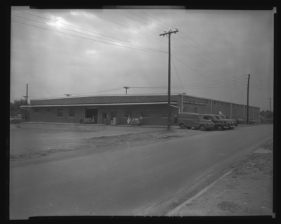 Kentucky Food Stores Warehouse (Delaware Avenue); exterior, men                             standing next to loading dock doors, delivery trucks parked in front of                             building