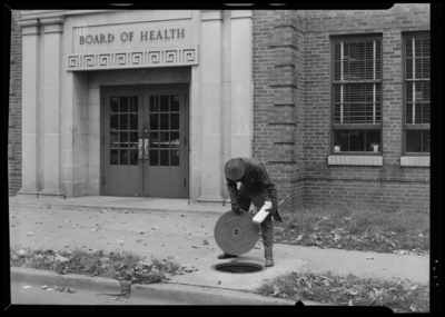 Man Hold Cover; in front of the Public Health Center (227 North                             Upper), exterior; man lifting man hole cover