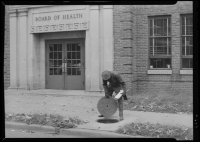 Man Hold Cover; in front of the Public Health Center (227 North                             Upper), exterior; man lifting man hole cover