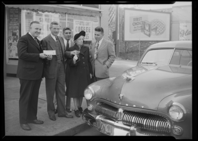 Kroger Store, 726 East Main; presentation of car; exterior; group                             of men and a woman standing next to a car