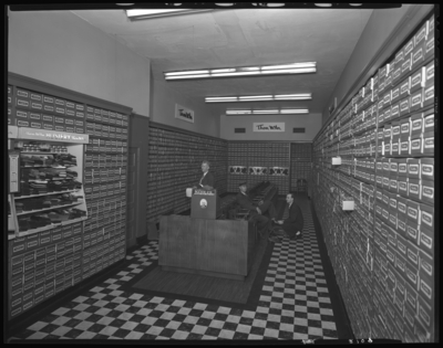 Thom McAn Shoe Company, 114 West Main; interior; man being waited                             on