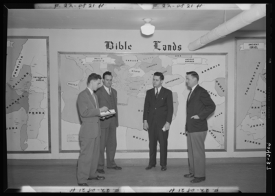 Belle of the Blue; Georgetown College; interior; group of men                             standing in front of wall display for 