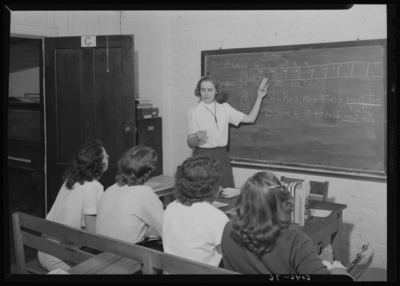 Belle of the Blue; Georgetown College; interior; classroom;                             Physical Education (PE) instructor standing at the chalkboard                             instructing students on the scoring for bowling