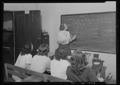 Belle of the Blue; Georgetown College; interior; classroom;                             Physical Education (PE) instructor standing at the chalkboard                             instructing students on the scoring for bowling