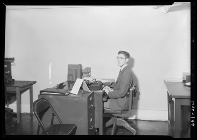 Belle of the Blue; Georgetown College; office; interior; man                             seated at a desk typing