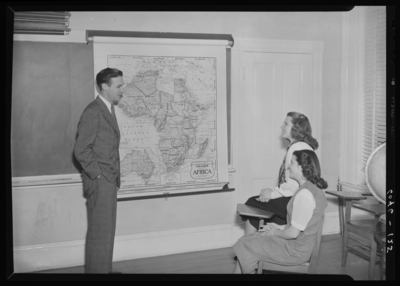 Belle of the Blue; Georgetown College; classroom; interior; two                             women seated, man standing in front of class next to map of                             Africa