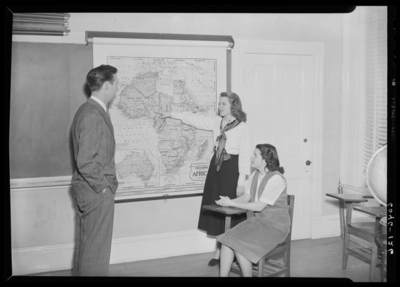 Belle of the Blue; Georgetown College; classroom; interior; woman                             standing next to map of Africa, man standing in front of class next to                             map of Africa; woman seated