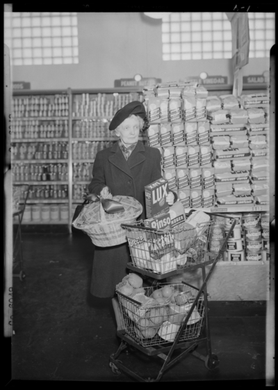 Kroger Store; 726 East Main; interior; woman standing beside her                             shopping basket holding a basket of grocery coupons