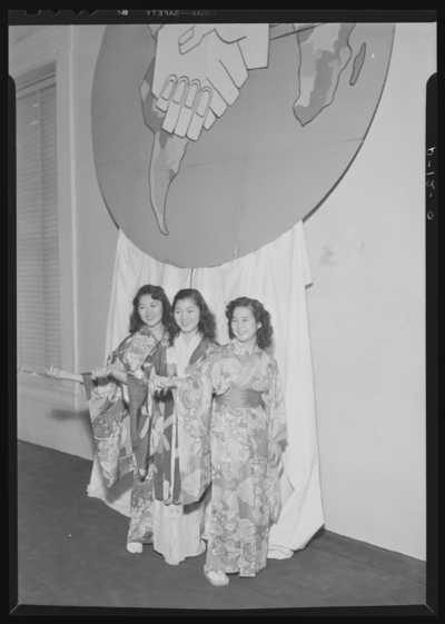 Belle of the Blue; Georgetown College; interior; three Asian                             women dressed in kimonos standing beneath display of the world globe                             with hands shaking