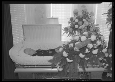 Ben Dotson (Police Officer); corpse; open casket surrounded by                             flowers; clothed in police uniform