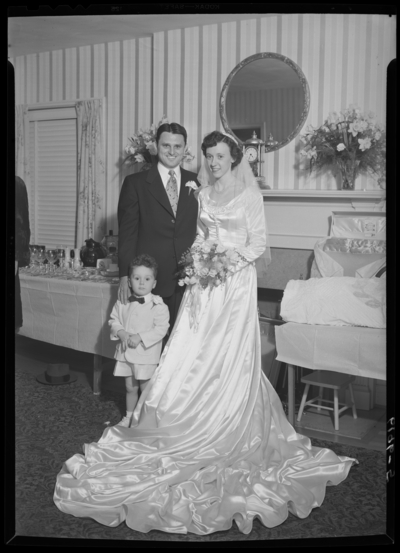 Fisher-Farris wedding; interior; bride and groom standing beside                             a little boy; group portrait