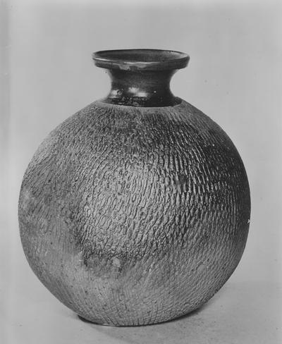 A ceramic pot by John Tuska. An oval shaped pot, which according to the print, is eight inched high