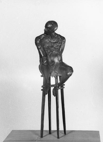 A bronze sculpture of a male nude on a high chair by John Tuska. This sculpture is one of the Italy inspired bronzes created during and after Tuska's trip to Italy in 1969