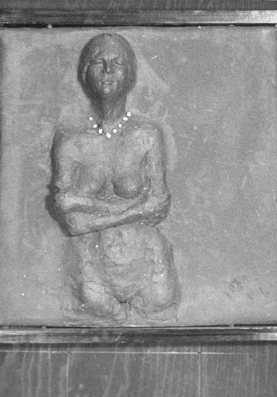 A ceramic tile relief of a female nude with beads and arms crossed by John Tuska