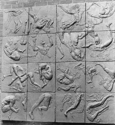 A ceramic relief of male nudes falling entitled 