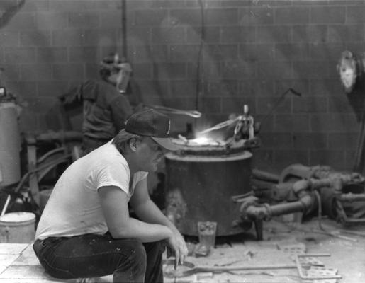 Two unidentified men heating bronze for the John Sherman Cooper bust in the University of Kentucky foundry