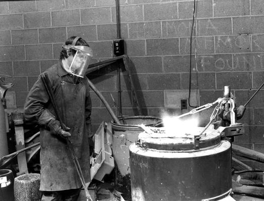 An unidentified man heating bronze for the John Sherman Cooper bust in the University of Kentucky foundry