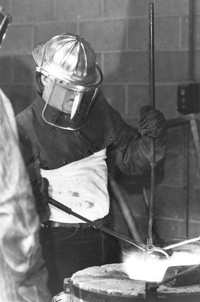 An unidentified man checking the furnace while heating bronze for the John Sherman Cooper bust in the University of Kentucky foundry