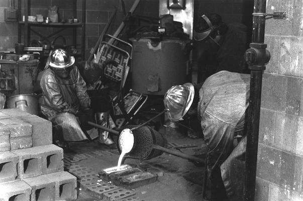 An unidentified man and Jack Gron pouring out bronze from the crucible used for casting of the John Sherman Cooper bust