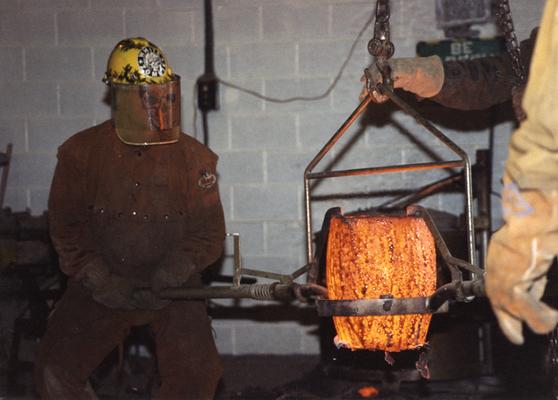 Andrew Marsh lifting a crucible in the University of Kentucky foundry for the casting 