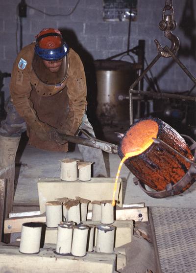 Scott Oberlink pouring bronze from a crucible in the University of Kentucky foundry for the casting 
