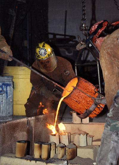 Andrew Marsh and Scott Oberlink pouring bronze from a crucible in the University of Kentucky foundry for the casting 
