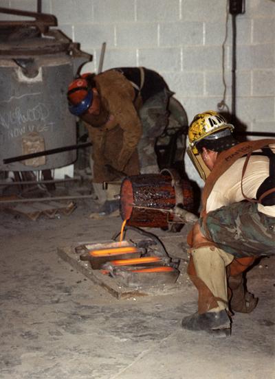 Scott Oberlink and Andrew Marsh pouring bronze from a crucible in the University of Kentucky foundry for the casting 