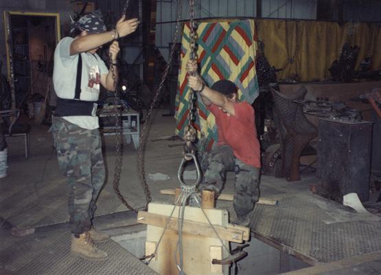 Andrew Marsh and Scott Oberlink lifting sand molds in the University of Kentucky foundry during the casting 