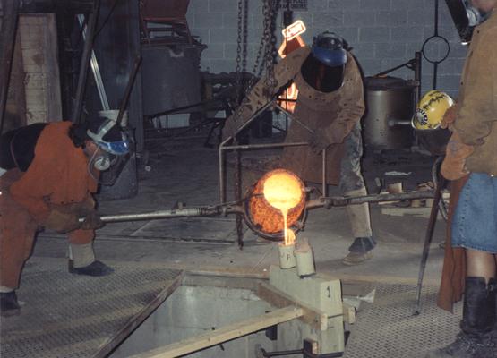 An unidentified man, Scott Oberlink, Andrew Marsh and Jack Gron pouring bronze in the University of Kentucky foundry for 