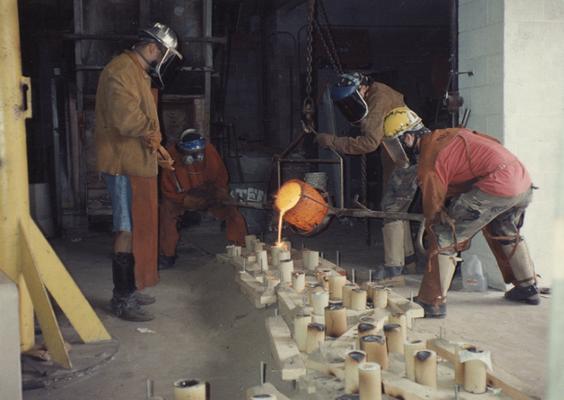 Jack Gron, an unidentified man, Scott Oberlink and Andrew Marsh pouring bronze in the University of Kentucky foundry for 