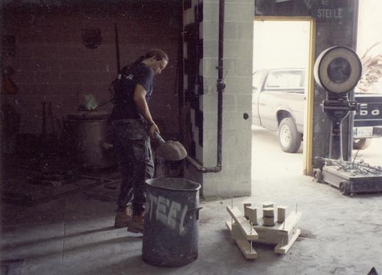 Scott Oberlink shoveling sand in the University of Kentucky foundry during the casting of 