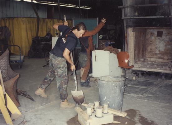 Scott Oberlink shoveling sand in preparation to pouring bronze in the University of Kentucky foundry for the casting of 