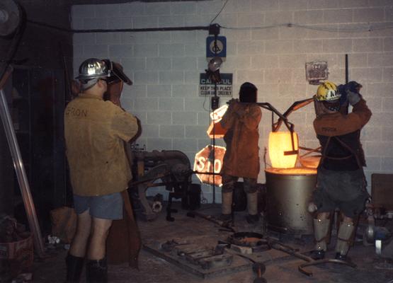 Jack Gron, Scott Oberlink and Andrew Marsh lifting a crucible out of the furnace in the University of Kentucky foundry for the casting of 