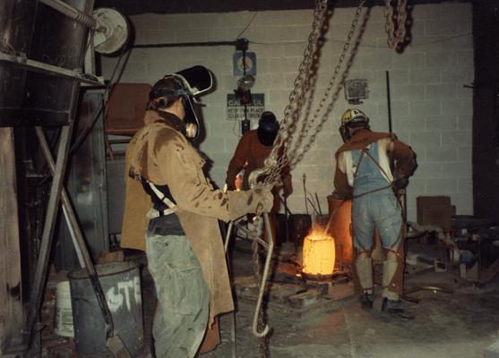 Scott Oberlink, an unidentified man and Andrew Marsh preparing to pour bronze in the University of Kentucky foundry for the casting of 