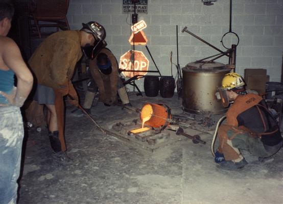 An unidentified man, Jack Gron, Scott Oberlink and Andrew Marsh pouring bronze in the University of Kentucky foundry for the casting of 