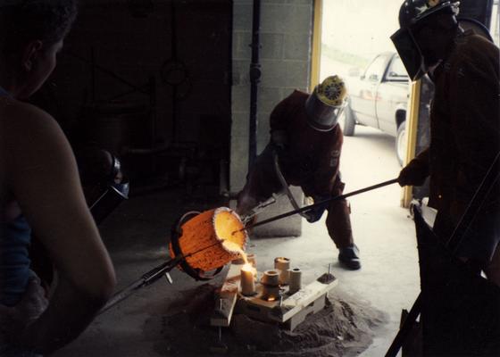 An unidentified man, Scott Oberlink, Andrew Marsh and Jack Gron pouring bronze in the University of Kentucky foundry for the casting of 