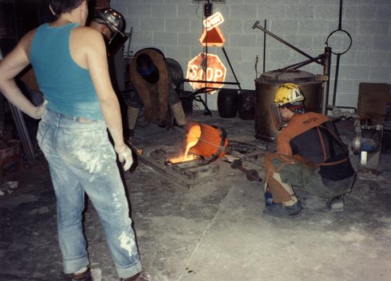 An unidentified man, Jack Gron, Scott Oberlink and Andrew Marsh pouring out bronze in the University of Kentucky foundry for the casting of 