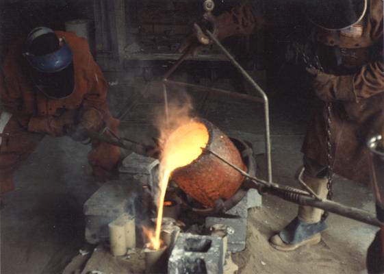 An unidentified man and Scott Oberlink pouring bronze in the University of Kentucky foundry for the casting of 