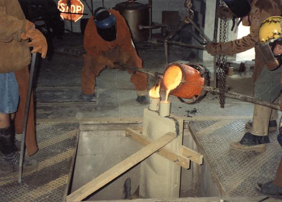 Jack Gron, an unidentified man, Scott Oberlink and Andrew Marsh pouring bronze in the University of Kentucky foundry for the casting of 