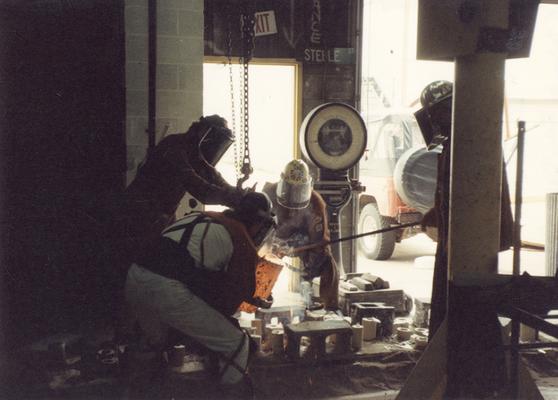 Scott Oberlink, an unidentified man, Andrew Marsh and Jack Gron pouring bronze in the University of Kentucky foundry for the casting of 