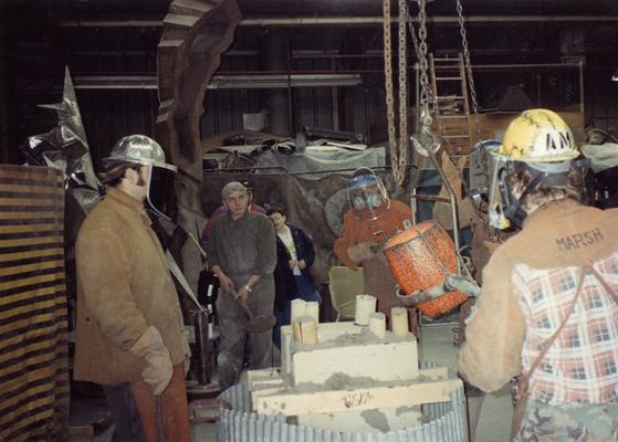 Jack Gron, an unidentified man, Seth Tuska, Jason Tuska, an unidentified man, Scott Oberlink and Andrew Marsh pouring bronze in the University of Kentucky foundry for the casting of 