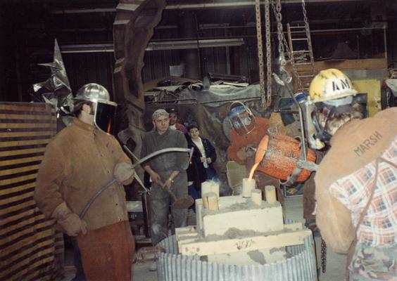 Jack Gron, an unidentified man, Seth Tuska, Jason Tuska, an unidentified man, Scott Oberlink and Andrew Marsh pouring bronze in the University of Kentucky foundry for the casting of 