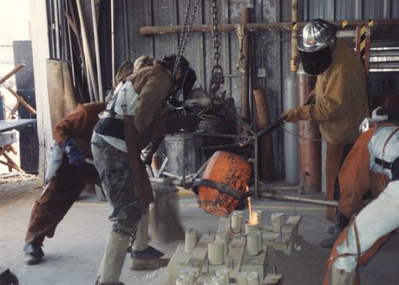 Andrew Marsh, Scott Oberlink, Jack Gron and an unidentified man pouring bronze in the University of Kentucky foundry for the casting of 