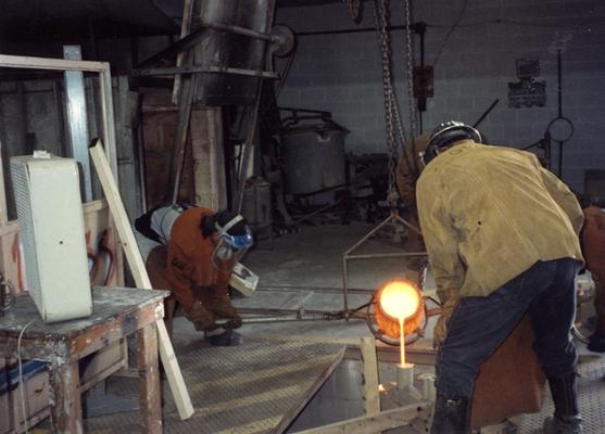 An unidentified man, Scott Oberlink, Jack Gron and Andrew Marsh pouring bronze in the University of Kentucky foundry for the casting of 