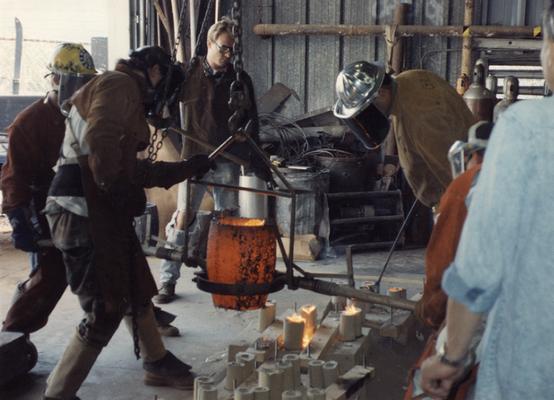 Andrew Marsh, Scott Oberlink, an unidentified man, Jack Gron and two unidentified people pouring bronze in the University of Kentucky foundry for the casting of 