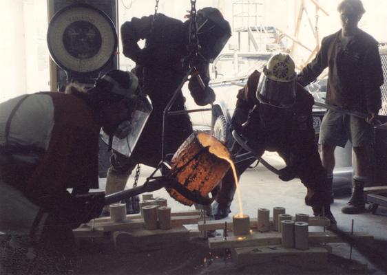 An unidentified man, Scott Oberlink, Andrew Marsh and an unidentified man pouring bronze in the University of Kentucky foundry for the casting of 