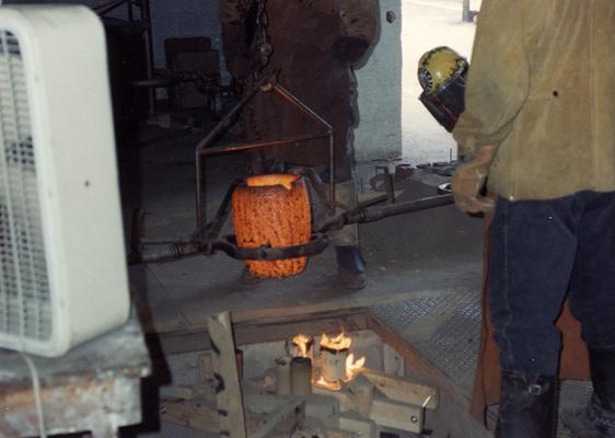 Scott Oberlink, Andrew Marsh and an unidentified man pouring bronze in the University of Kentucky foundry for the casting of 